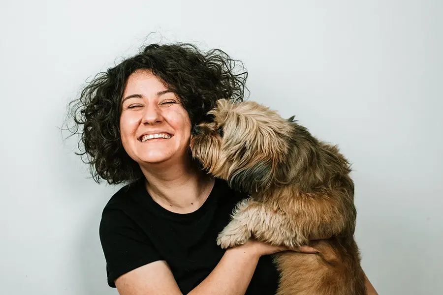 Woman getting her face licked by fluffy brown dog